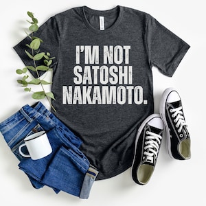 May include: A dark heather grey t-shirt with the text "I'M NOT SATOSHI NAKAMOTO." printed in white.