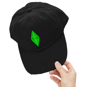 Könnte beinhalten: Schwarze Baseballkappe mit einem grünen Diamanten-Logo. Der Diamant ist eine stilisierte Grafik eines grünen Edelsteins.