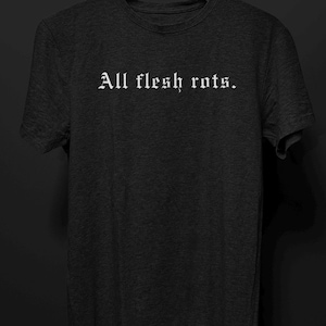 K&ouml;nnte beinhalten: Dunkelgraues T-Shirt mit dem wei&szlig;en Schriftzug "All flesh rots" in gotischer Schrift. Das Shirt hat einen Rundhalsausschnitt und kurze &Auml;rmel. Der Hintergrund ist einfarbig schwarz.