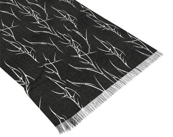 May include: Black scarf with a white abstract pattern of branches. The scarf has a fringed edge.