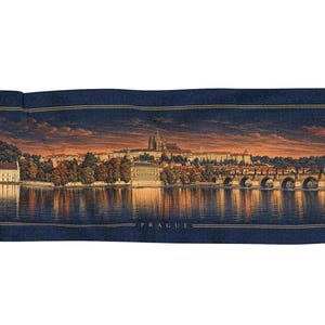 Op de afbeelding: Een rechthoekig geweven wandkleed met een panoramisch uitzicht op Praag bij zonsondergang. De scène toont de rivier de Moldau, de Karelsbrug en de Praagse Burcht onder een donkeroranje lucht. Het woord PRAGUE staat in goudkleurige letters onderaan.