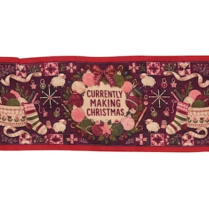 May include: A rectangular woven table runner with a dark red background featuring the text CURRENTLY MAKING CHRISTMAS in the center. The design includes yarn balls, knitting needles, stockings, sheep, and floral patterns with fringed edges.