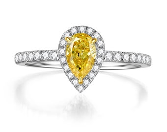 May include: A pear-shaped yellow diamond engagement ring with a halo of smaller diamonds set in a white gold band.