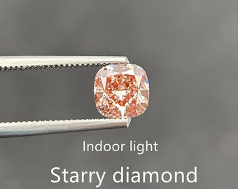 May include: A close-up of a pink and orange diamond, with a cushion cut, held in tweezers. The diamond is reflecting light, creating a starry effect. The text "Indoor light" and "Starry diamond" is visible below the diamond.