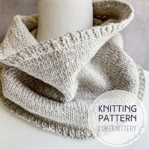 May include: A gray knitted cowl neck scarf with a folded over edge. The scarf is made with a textured stitch pattern. The text "Knitting Pattern LuxeKnittery" is on a white circle in the lower right corner of the image.