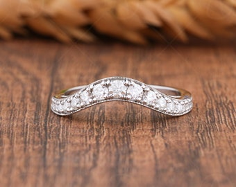 May include: A silver curved wedding band with a row of small, clear diamonds.