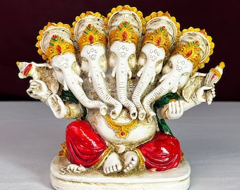 May include: A white figurine of Ganesha, the Hindu god of wisdom and prosperity, with five heads and four arms. The figurine is decorated with red, green, gold, and white paint.