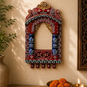 Könnte beinhalten: Ein dekorativer Wandrahmen aus Holz in Form eines Bogenfensters, bemalt in leuchtendem Rot, Blau, Grün und Gold. Der Rahmen zeigt aufwendige, handgemalte weiße Blumenmuster, zwei blaue Säulen, eine Gitterbasis und fünf kleine Haken zum Aufhängen.