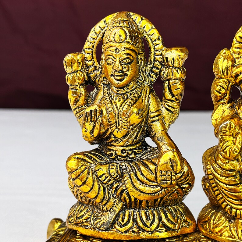 May include: Gold-toned metal statue of a Hindu goddess sitting on a turtle. The goddess is wearing a crown and ornate clothing.