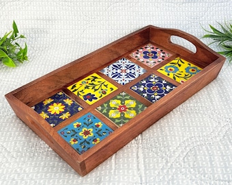 Può includere: Un vassoio rettangolare in legno con un manico decorativo. Il vassoio è decorato con nove piastrelle in ceramica colorate con motivi floreali.