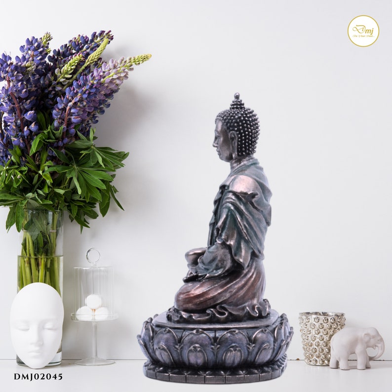 May include: A bronze-colored Buddha statue sitting in a meditative pose on a lotus base. The statue is detailed with a green robe and a serene expression.