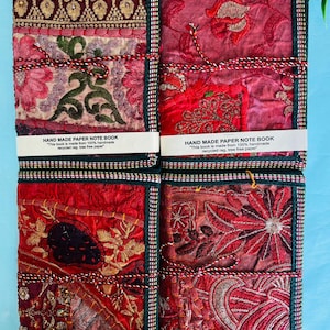 Puede incluir: Cuatro cuadernos hechos a mano con coloridas cubiertas de tela bordada. Los cuadernos están encuadernados con hilo y presentan el texto "HAND MADE PAPER NOTE BOOK". Las cubiertas son rojas, burdeos y doradas.