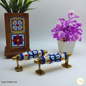 Può includere: Due pomelli per armadi in ceramica con base bianca e disegni floreali blu e arancioni. I pomelli hanno una finitura in ottone e sono montati su una base in ottone.