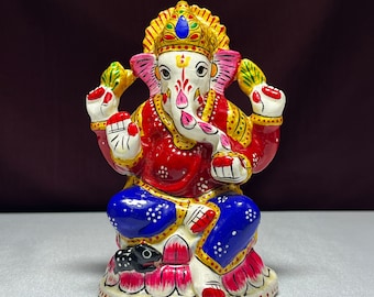 May include: A colorful, hand-painted metal statue of the Hindu deity Ganesha. The statue depicts Ganesha sitting on a lotus flower with a mouse at his feet. He is adorned with a crown, jewelry, and a red and blue robe.