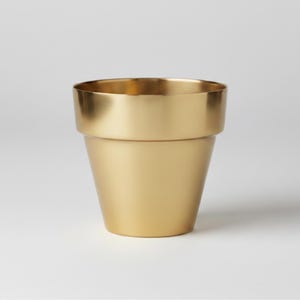 May include: A gold-coloured metal planter with a wide, slightly flared rim. The planter has a simple, modern design, with a cylindrical body that tapers slightly towards the base. The surface has a matte finish. Suitable for indoor plants.