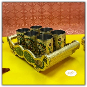 Puede incluir: Un juego de seis vasos de color dorado con dise&ntilde;os de pavo real, dispuestos en una bandeja dorada con dise&ntilde;os de pavo real. La bandeja tiene un asa en un lado.