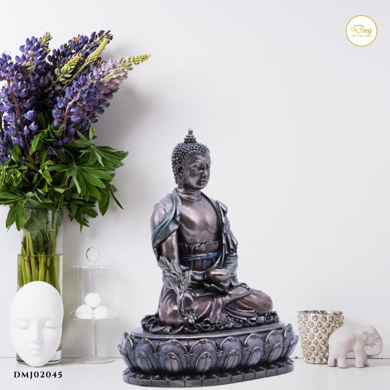 May include: A bronze-colored Buddha statue sitting in a meditative pose on a lotus flower base. The statue has a serene expression and is decorated with intricate details.