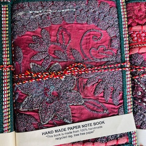 Peut inclure: Carnet de notes fait à la main avec une couverture brodée de fleurs bordeaux. Le carnet est orné d'une bordure verte et dorée et est lié avec une corde décorative. Le texte sur l'étiquette indique "HAND MADE PAPER NOTE BOOK".