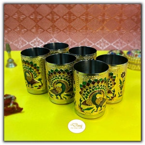 Puede incluir: Seis vasos de beber de metal de color dorado con dise&ntilde;os de pavo real. Los vasos tienen un dise&ntilde;o de pavo real verde, dorado y rojo sobre un fondo dorado.