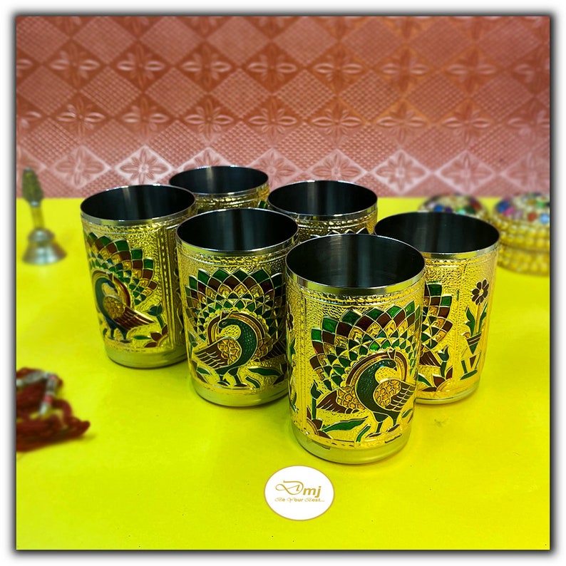 Puede incluir: Seis vasos de beber de metal de color dorado con dise&ntilde;os de pavo real. Los vasos tienen un dise&ntilde;o de pavo real verde, dorado y rojo sobre un fondo dorado.