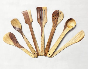 May include: Set of seven wooden kitchen utensils, including a slotted spoon, a spatula, a ladle, a spoon, and three different types of spoons. The utensils are made of dark brown wood with a natural wood grain.