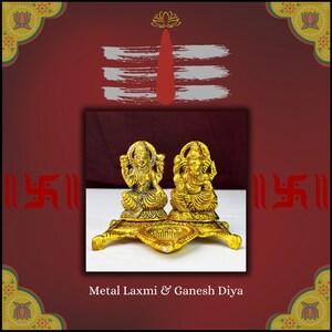May include: Gold metal diya with a depiction of Lakshmi and Ganesh. The diya has three legs and a star-shaped base.