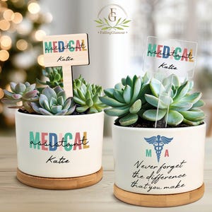 May include: Two white ceramic succulent planters with wooden bases. One has a wooden sign that reads "MEDICAL assistant Katie." The other has a clear acrylic sign with the same text. Both planters have the text "MEDICAL assistant Katie."