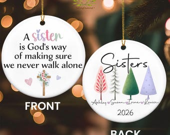 May include: Two round white ceramic ornaments with gold hanging strings. The first features the text A sister is God's way of making sure we never walk alone and a floral cross. The second shows four stylized trees, the text Sisters, 2026, and names.