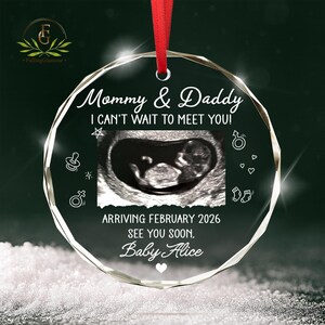 May include: A clear, round ornament with a red ribbon. The ornament features the text "Mommy & Daddy, I can't wait to meet you!" and an ultrasound image. It also includes the text "Arriving February 2026, See you soon, Baby Alice."