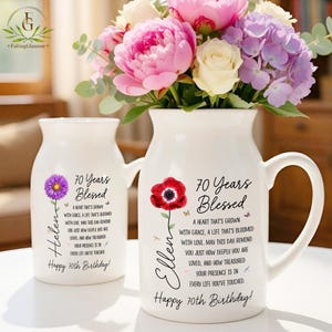 May include: Two white ceramic pitchers featuring floral illustrations and the text 70 Years Blessed. One pitcher displays a purple flower and the name Helen, while the other shows a red poppy and the name Ellen, with birthday wishes.
