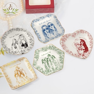 May include: A collection of decorative ceramic plates in various shapes, including round, square, and heart-shaped. Each plate features a unique illustration of people and floral borders, with text such as "Soul sister forever" and "Bestfriends for life".