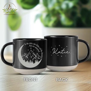 May include: Black ceramic mug with a white design of a crescent moon and mountains. The text "To the stars who listen and the dreams that are answered" is on the front of the mug. The back of the mug has the name "Katie" in white lettering.