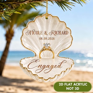 May include: A white seashell-shaped ornament with gold trim, featuring the text "NICOLE & RICHARD", the date "08.09.2026", and the word "Engaged" in gold script. A diamond ring is centered on the shell. Includes text: "2D FLAT ACRYLIC NOT 3D".