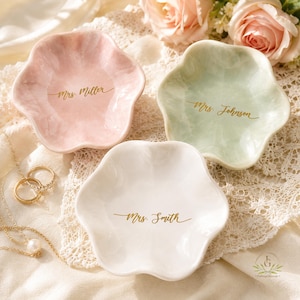 May include: Three flower-shaped trinket dishes in pastel pink, pale green, and white. Each dish features a glossy finish and gold cursive text reading Mrs. Miller, Mrs. Johnson, and Mrs. Smith respectively, centered on the smooth interior surface.