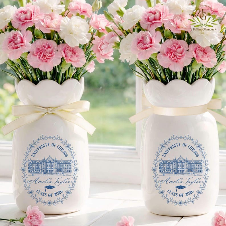 Pu&ograve; includere: Due vasi in ceramica bianca con bordi smerlati, ciascuno legato con un nastro color crema, contengono bouquet di garofani rosa e bianchi. I vasi presentano un disegno blu con il testo "UNIVERSITY OF CHICAGO", un nome e "CLASS OF 2026".