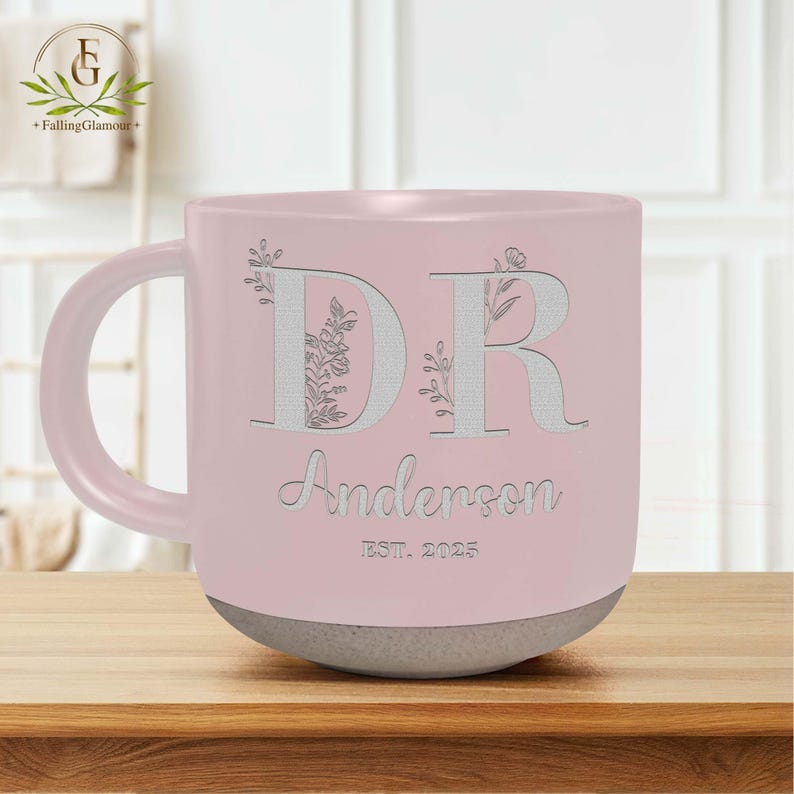 May include: A pink ceramic mug with a white floral design and the letters "DR" with the name "Anderson" and "EST. 2025" below.