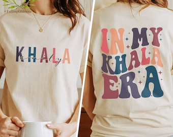 Könnte beinhalten: Ein beiges T-Shirt mit dem Text "KHALA family" auf der Vorderseite und "IN MY KHALA ERA" auf der Rückseite. Der Text ist in einer retro-farbigen Schrift.