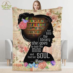 May include: A beige throw blanket featuring a silhouette of a woman's head with a library inside. The blanket has floral and script designs, with the text "And Into the library she goes to lose her mind and find her SOUL Alysa."