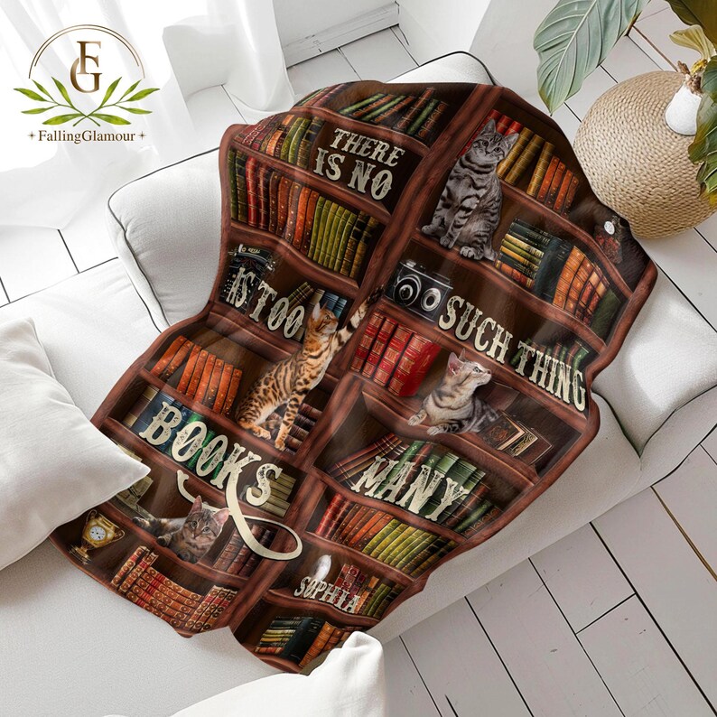 May include: A brown and white throw blanket with a bookshelf design featuring cats and books. The text on the blanket reads "There is no such thing as too many books".