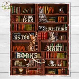 May include: A brown wooden bookshelf filled with books, with three cats sitting on the shelves. The text on the bookshelf reads "There is no such thing as too many books".