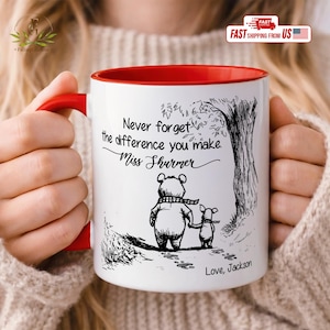 May include: White ceramic mug with a red interior and handle. The mug features a black and white illustration of a bear and pig walking together under a tree. Text reads "Never forget the difference you make, Miss Shurmer" and "Love, Jackson."