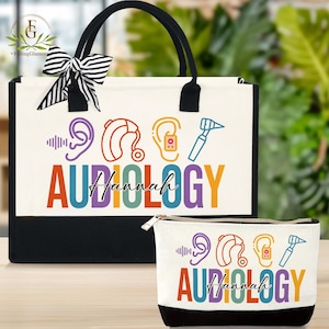 May include: A white tote bag and matching cosmetic bag with black accents. Both bags feature colorful graphics related to audiology, including hearing aids and an otoscope, with the word "Audiology" and a name. A black and white striped bow adorns the tote.
