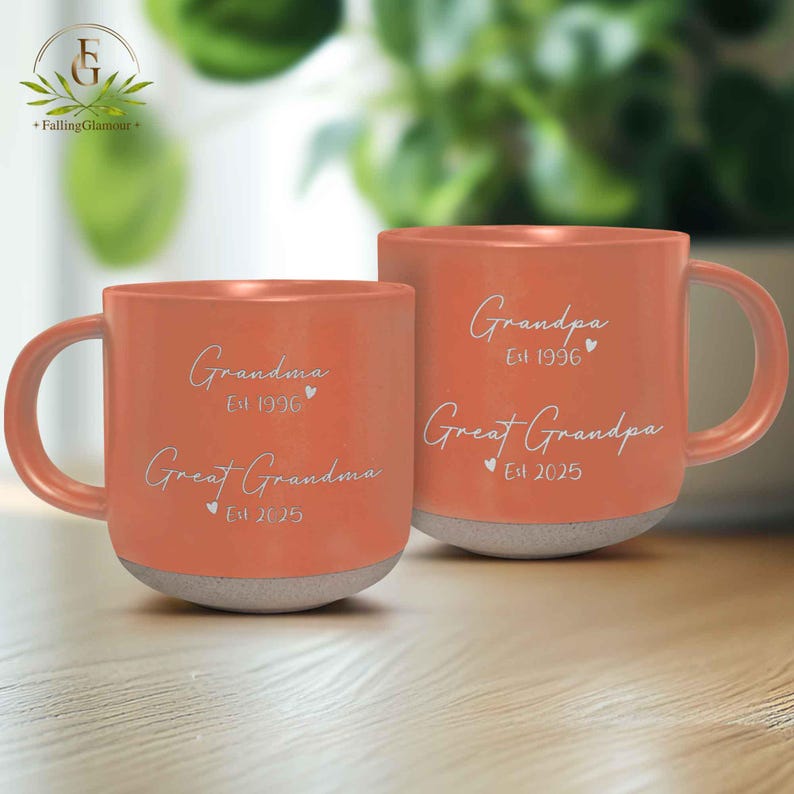 May include: Two orange ceramic mugs with white text. The mug on the left says "Grandma Est 1996 Great Grandma Est 2025". The mug on the right says "Grandpa Est 1996 Great Grandpa Est 2025".