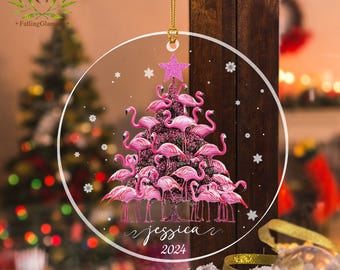 Può includere: Un ornamento natalizio a forma di fenicottero rosa con un motivo a fiocco di neve bianco e il testo "jessica 2024".