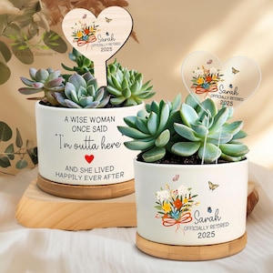 May include: Two succulent plants in white ceramic pots with wooden bases. One pot has the text "A WISE WOMAN ONCE SAID 'I'm outta here' AND SHE LIVED HAPPILY EVER AFTER." The other pot has the text "Sarah OFFICIALLY RETIRED 2025."