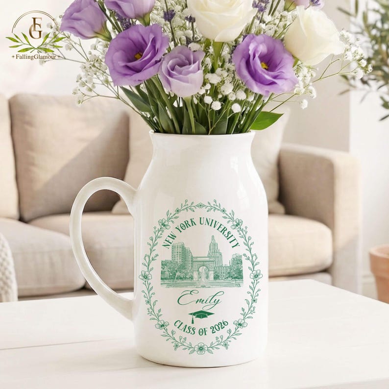 Pu&ograve; includere: Un vaso a forma di brocca in ceramica bianca con manico, pieno di fiori viola e bianchi. Il vaso presenta un disegno verde dello skyline della New York University, il nome "Emily" e "Classe del 2026" in una ghirlanda floreale.