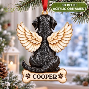 May include: A 3D relief acrylic ornament featuring a black dog with large cream-colored angel wings, sitting on a bone-shaped base with the name COOPER and paw prints printed on it, suspended by a red ribbon.