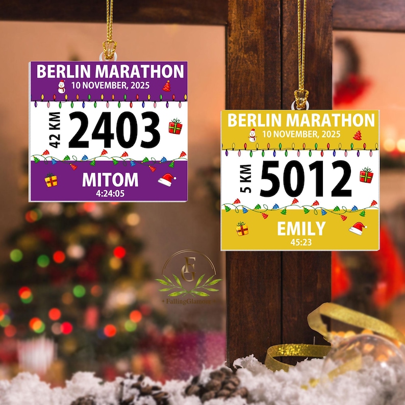 May include: Two square hanging ornaments featuring Berlin Marathon race bib designs. One is purple with the number 2403 and name MITOM, the other is yellow with the number 5012 and name EMILY. Both include the date 10 November 2025 and holiday graphics.