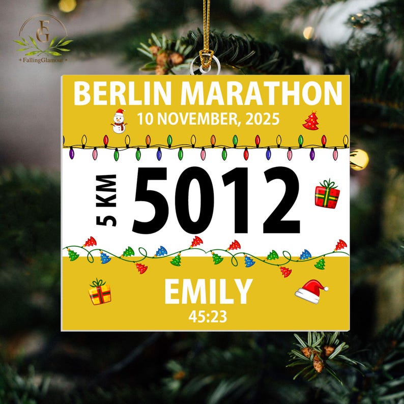 May include: A square yellow and white ornament featuring the text BERLIN MARATHON, 10 NOVEMBER, 2025, 5 KM, 5012, EMILY, and 45:23. The design includes colorful Christmas light strings, a snowman, a gift box, and a Santa hat on a gold string.