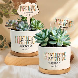 May include: Two white ceramic succulent pots with a wooden base. The pots feature a colourful graphic design with the text "Front Office Squad" and the name "Jenifer".